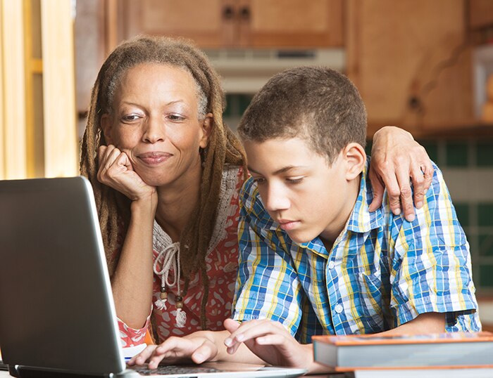 A kid and his mother look at laptop