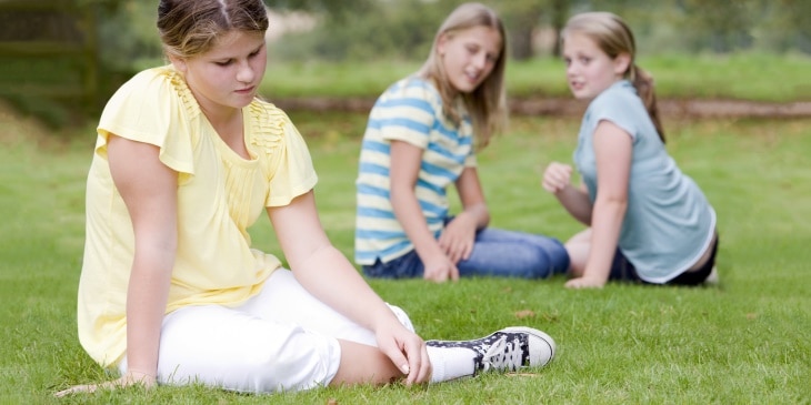 Girls bullying another girl outdoors